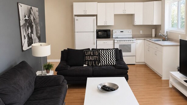 Una sala de estar moderna con un sofá negro, una mesa de centro blanca y un sillón de cuero marrón.