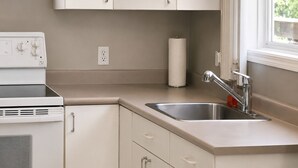 Una cocina con estufa integrada, un lavamanos con grifo moderno y una ventana con vistas al verdor.