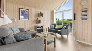 Ein modernes Wohnzimmer mit einer Couch, Sesseln, einem Couchtisch und einem Bücherregal.