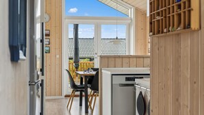 Eine moderne Küche mit Geschirrspüler, Holzschränken und einem Essbereich mit Tisch und Stühlen.