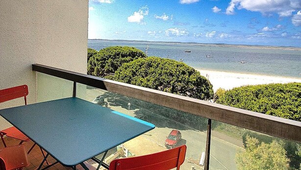 Varanda com mesa e cadeiras, vista para a praia e o mar.