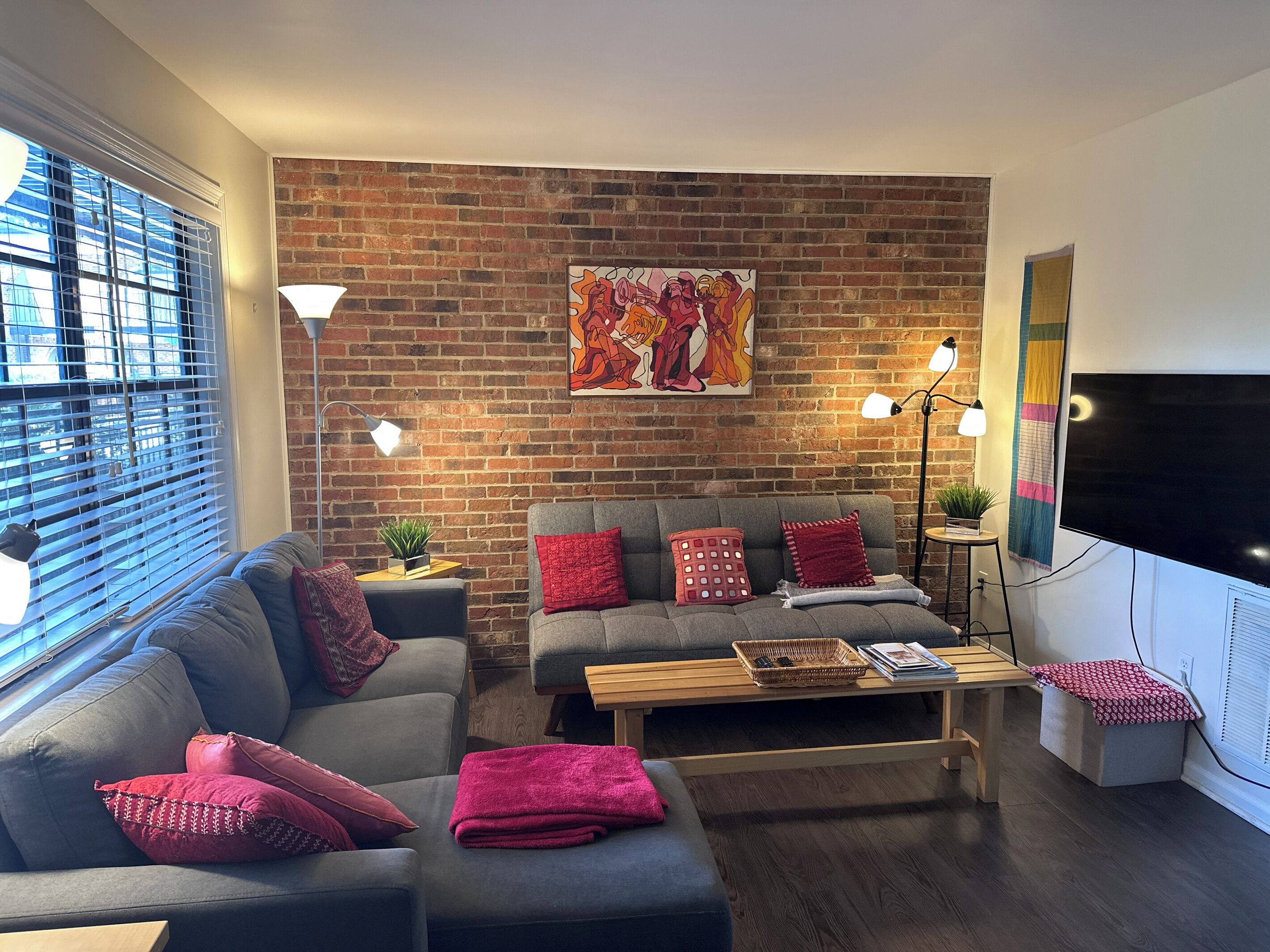 A living room with a brick wall, a sofa, a coffee table, and a TV.