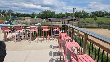 A deck with chairs and a view of a playground.