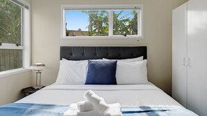 Een slaapkamer met een bed, een raam, een nachtkastje en een kledingkast.
