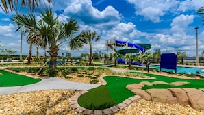 Un parco acquatico con un grande scivolo d'acqua blu, palme e area piscina.