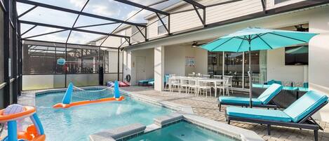 An indoor pool area with a hot tub, lounge chairs, and a covered seating area.