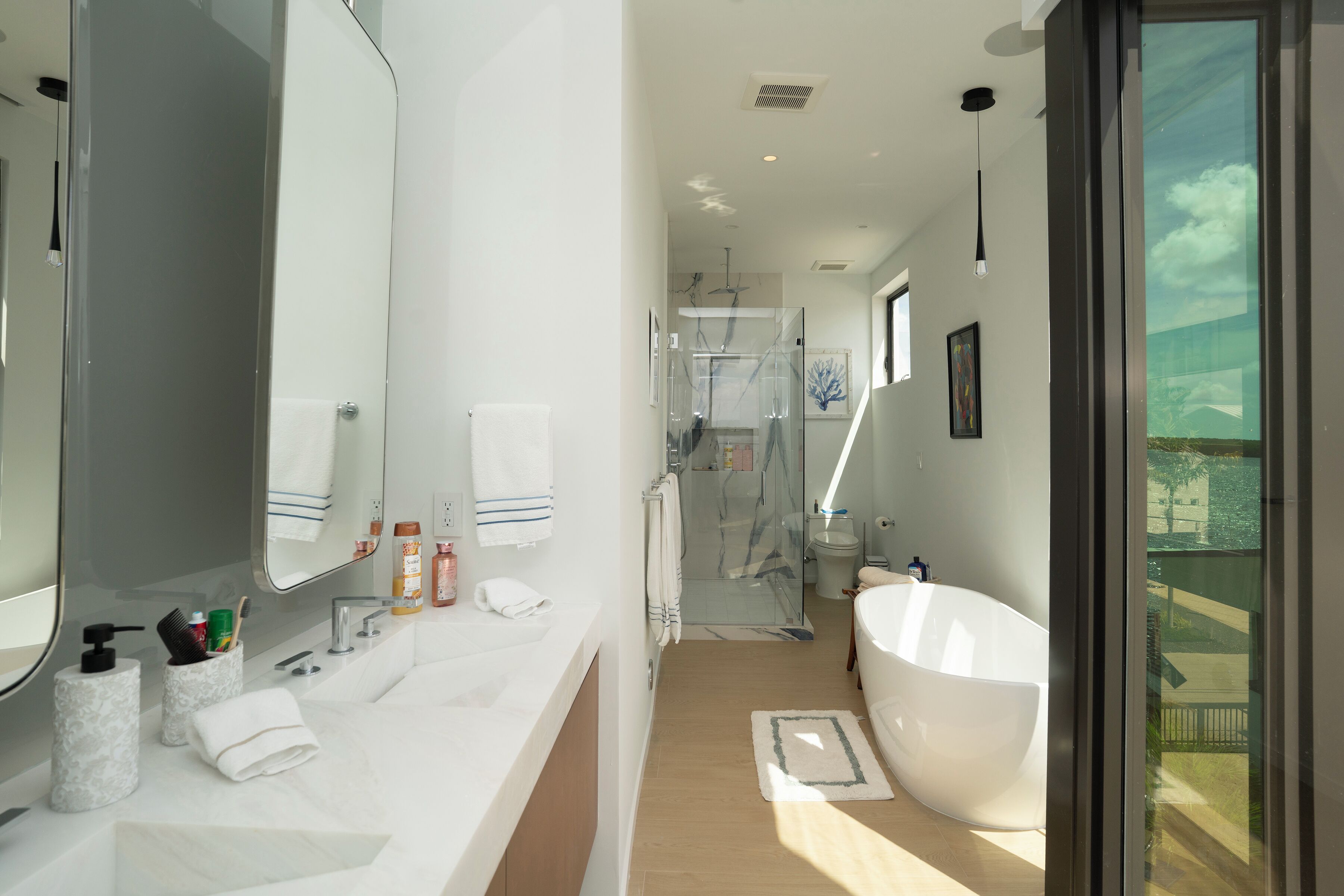 A modern bathroom with a large mirror, a white bathtub, and a shower area.
