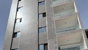 A multi-story building with a modern architectural design, featuring a series of balconies and large windows. - 301: 2-bedroom apartment in quaint Dakar with AC for a relaxing stay (Dakar)