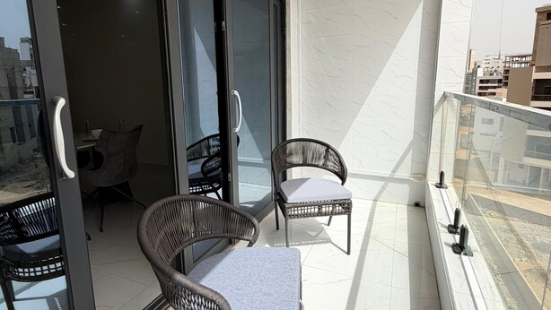A balcony with two wicker chairs, a sliding glass door, and an air conditioning unit. - 301: 2-bedroom apartment in quaint Dakar with AC for a relaxing stay (Dakar)
