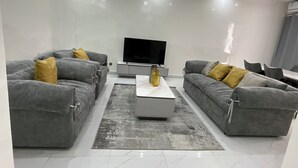 A modern living room with two grey sofas, a central coffee table, and a flat-screen TV. - 301: 2-bedroom apartment in quaint Dakar with AC for a relaxing stay (Dakar)