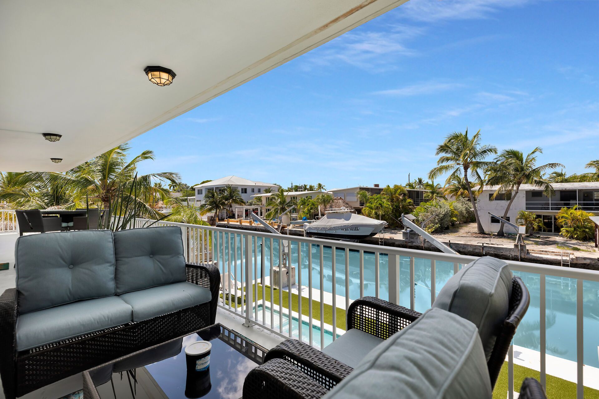 Ein Balkon mit Pool, Liegestühlen und Blick auf einen Resorthof mit Palmen und Gebäuden.