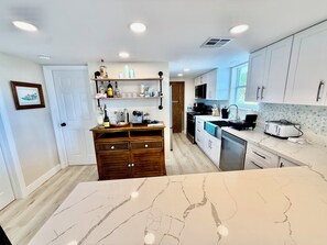 A modern kitchen with white cabinets, a marble countertop, and a wooden cabinet with bottles. - Canal front. Ocean access via Tavernier Creek. New pool and hot tub. Sleeps 8 (Tavernier)