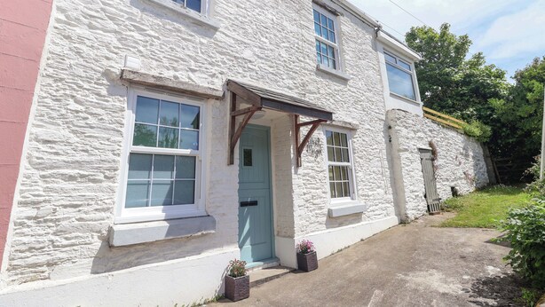 A white stone building with a green door, multiple windows, and a small porch. - Walnut Major (Kingsbridge)