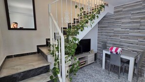 Un escalier avec des rampes blanches et un téléviseur dans l’espace de divertissement situé en contrebas.