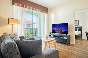 A modern living room with a sofa, a coffee table, and a TV displaying 'Walt Disney Studios'. - Spacious 3BR VistaCay Condo Near Disney, Universal & Orlando Attractions with Resort Amenities (Orlando)