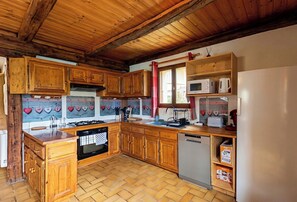A kitchen with wooden cabinets, a stove, a dishwasher, and a refrigerator. - CASA-La Bergerie vue montagne Saint-Véran (Molines-en-Queyras)