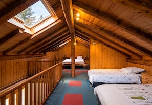 A cozy attic bedroom with a sloped ceiling, wooden walls, a skylight, and a bed with a patterned bedspread. - CASA-La Bergerie vue montagne Saint-Véran (Molines-en-Queyras)