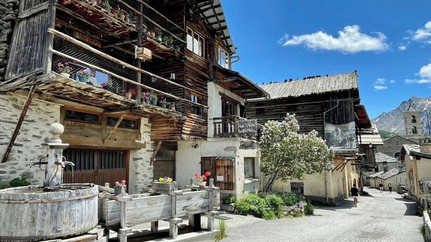 A traditional wooden building with balconies, a stone wall, and a clear sky. - CASA-La Bergerie vue montagne Saint-Véran (Molines-en-Queyras)