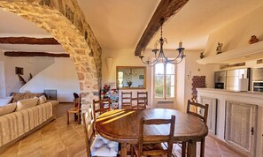 Un comedor rústico con pared de piedra, muebles de madera y una cocina moderna con electrodomésticos.