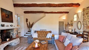 A living room with a fireplace, a sofa, a coffee table, and a staircase leading to another room. - CASA-Bouchra luxueux apt dans château provençal (Le Thoronet)