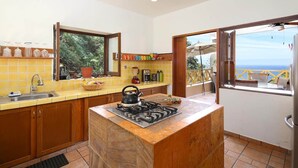 Une cuisine équipée d’une cuisinière à gaz, d’un évier et d’une fenêtre donnant sur un balcon.
