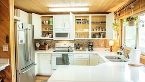 Une cuisine moderne avec des armoires blanches, des appareils en acier inoxydable et un grand îlot central doté d’un évier.