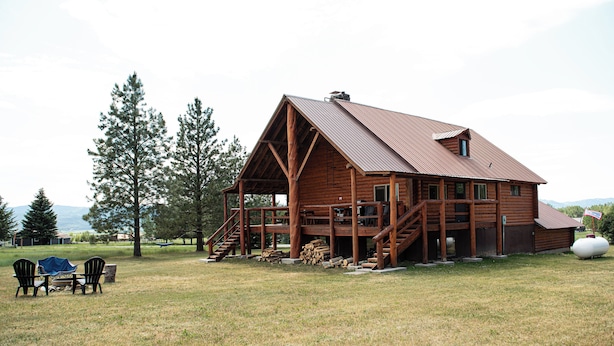 Une cabane en bois avec une véranda, un escalier et une grande fenêtre.