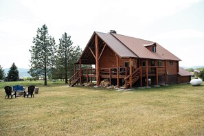 A wooden cabin with a porch, a staircase, and a large window. - Log cabin, mountain views, golf course, fire pit, near Jackson Hole, sleeps 10 (Star Valley Ranch)