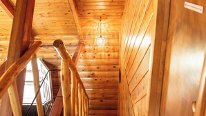 Un intérieur en bois avec un escalier, des murs en bois et un luminaire au plafond.