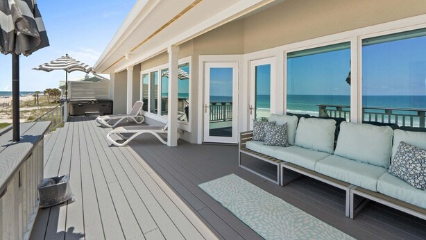 A deck with a sofa, lounge chairs, and umbrellas. - Fall Deals + Snowbird Rates | Gulf Front Beach Escape (St. George Island)