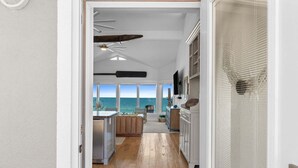 A modern kitchen with a view of the ocean, wooden flooring, and a ceiling fan. - Fall Deals + Snowbird Rates | Gulf Front Beach Escape (St. George Island)