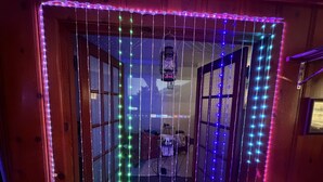 Een kamer met een houten deur, een kamerbreed tapijt met dessin en een hanglamp.