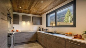 Une cuisine moderne avec des meubles en bois, une grande fenêtre et une vue sur l’extérieur.