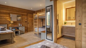 Une chambre avec un lit superposé, une table de chevet avec une lampe, une commode et un grand miroir.