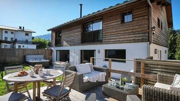 A wooden cabin with a patio area featuring outdoor furniture and a hot tub.
