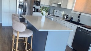 Een moderne keuken met een centraal eiland, roestvrijstalen apparatuur en houten vloeren.