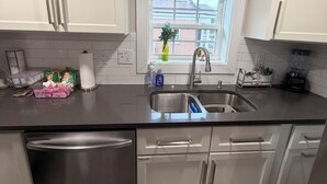A modern kitchen with stainless steel appliances, a window with a view, and a countertop with various items.
