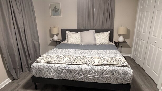 A bedroom with a large bed, two bedside tables with lamps, a ceiling light, and a wardrobe.