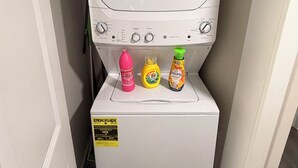 A compact washing machine with a control panel and three detergent bottles on top.