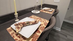 A dining area with a long table, two candles, and a decorative wall piece.