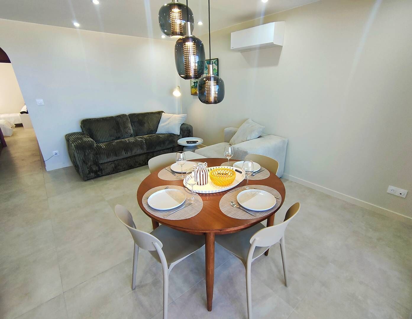 A dining area with a round table set for four, two white chairs, a yellow bowl, and plates.