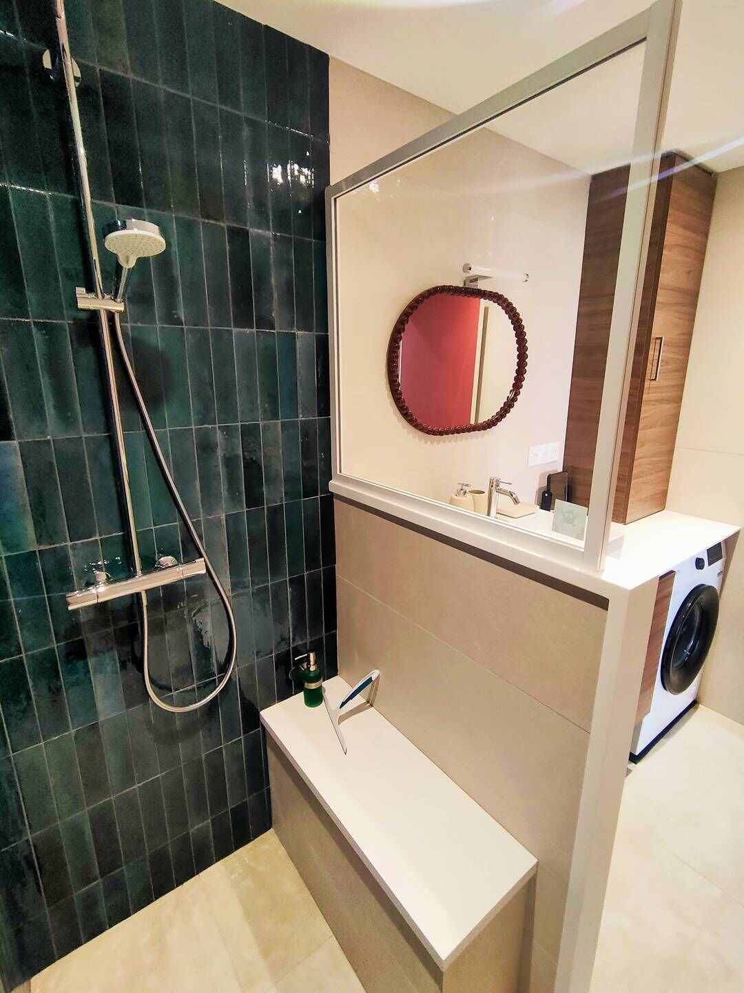 Une salle de bain moderne équipée d’une douche, d’un lavabo, d’un miroir et d’un lave-linge.