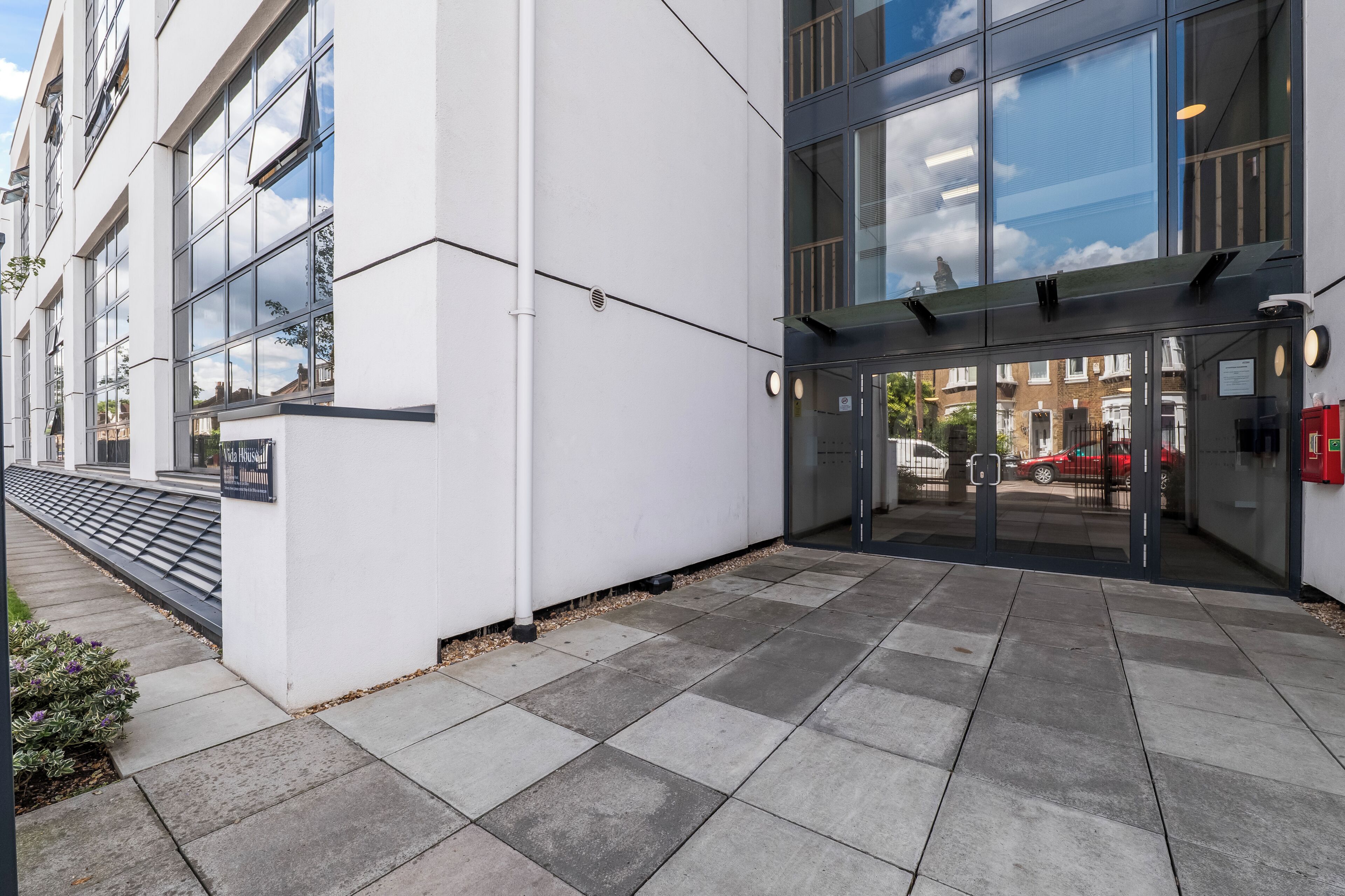 A modern building with large windows, a paved entrance area, and a visible fire hydrant.