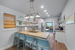 A modern kitchen with a central island, bar stools, and a view to the dining area.