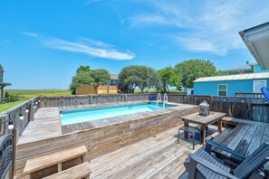Eine Holzterrasse mit Pool, Gartenmöbeln und Blick auf die Umgebung.
