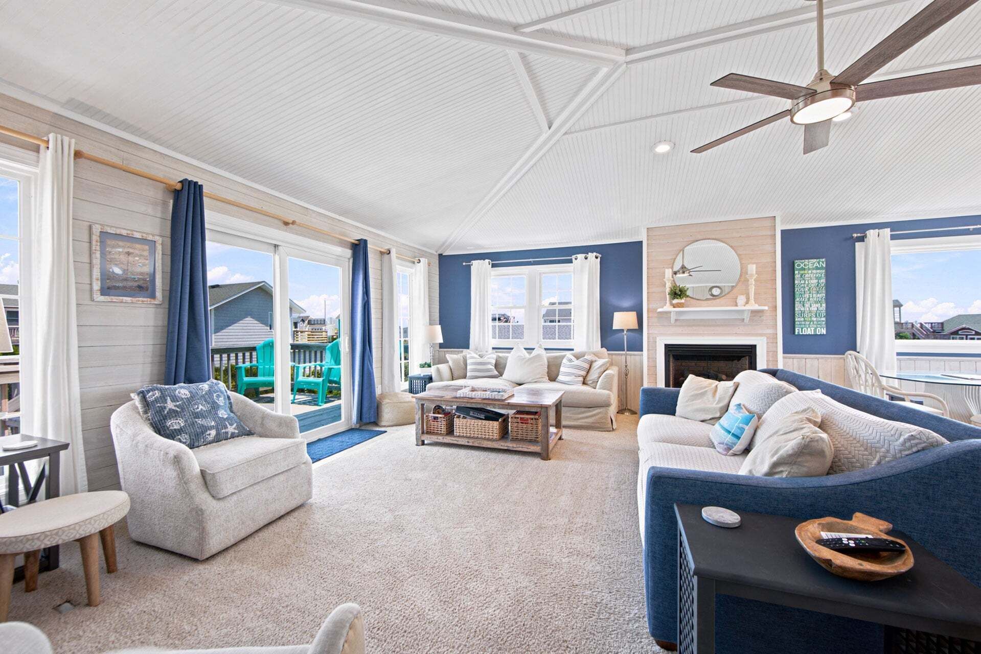 A spacious living room with a ceiling fan, a fireplace, and a view of the outside.