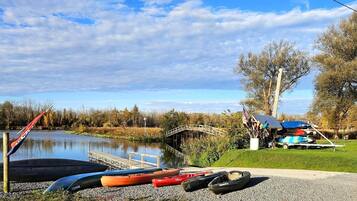 Une vue sur le lac, avec un quai, des kayaks, un espace de repos abrité et un petit pont.