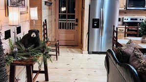 Un intérieur en bois comprenant un coin repas, une cuisine équipée d’appareils électroménagers en acier inoxydable et une décoration sur le thème de l’ours.