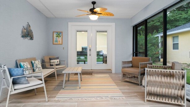 A spacious patio with a ceiling fan, a dining table, and comfortable seating. - Simply Divine Beach Home | Walk to Beach | Firepit | Pets | Sleeps 8 (Palm Coast)