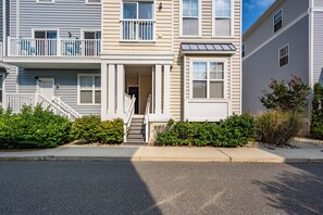 A two-story residential building with a front entrance, a staircase, and a small porch area. - Midtown 3BR Townhouse, Walk to Beach, Sleeps 10, Linens Included (Ocean City)